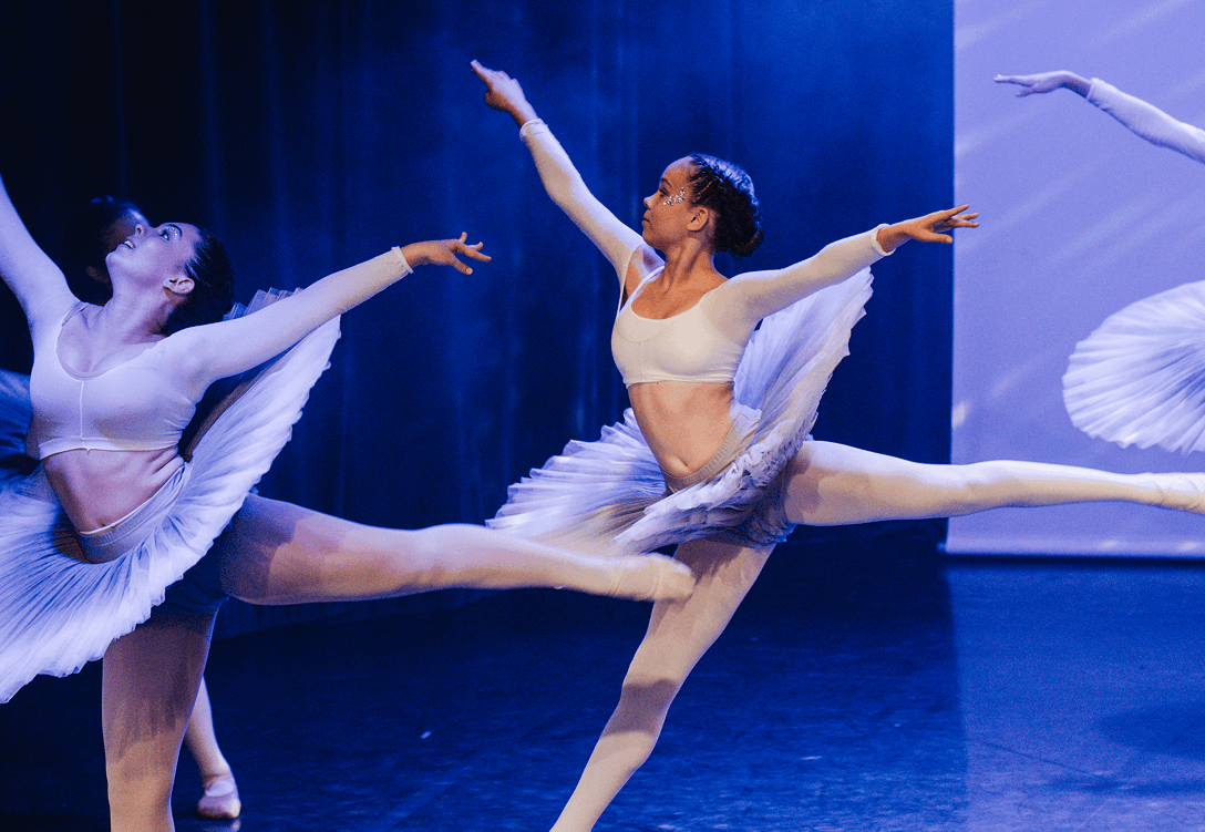 Danseuses en tutu blanc effectuant un saut gracieux sur scène.
