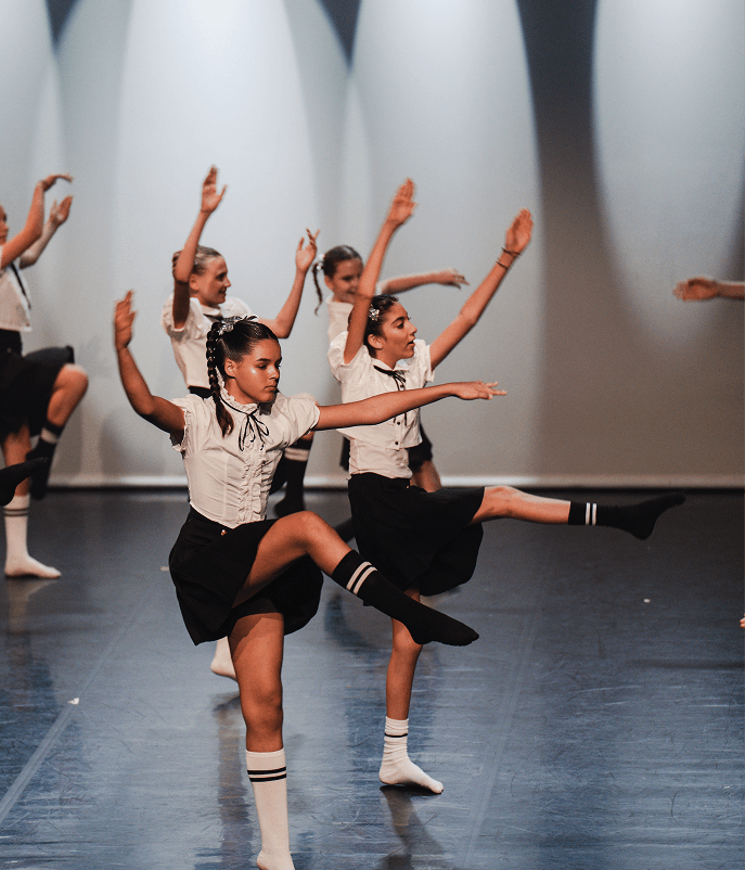 Des danseuses en uniforme exécutent une chorégraphie sur scène.