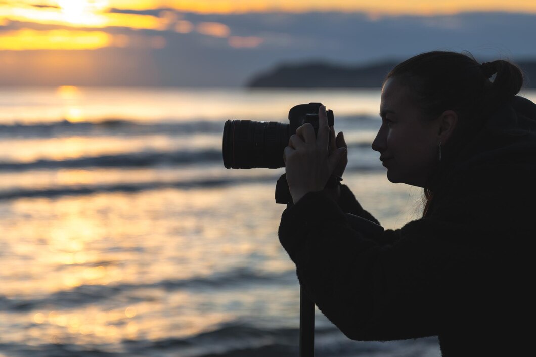 Photographe prenant des photos au coucher du soleil près de la mer.